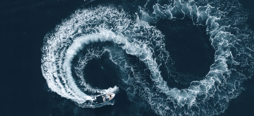 Aerial view of a boat creating circular waves in the water.